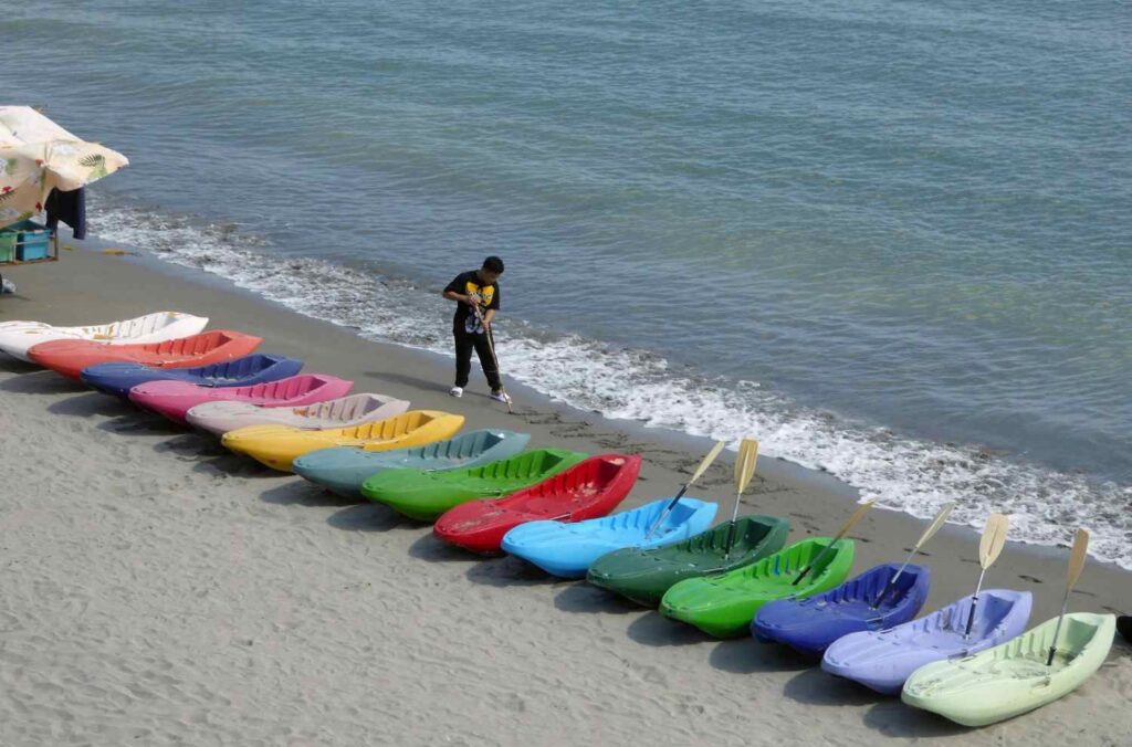 Colorful kayaks lined up on beach near water after use