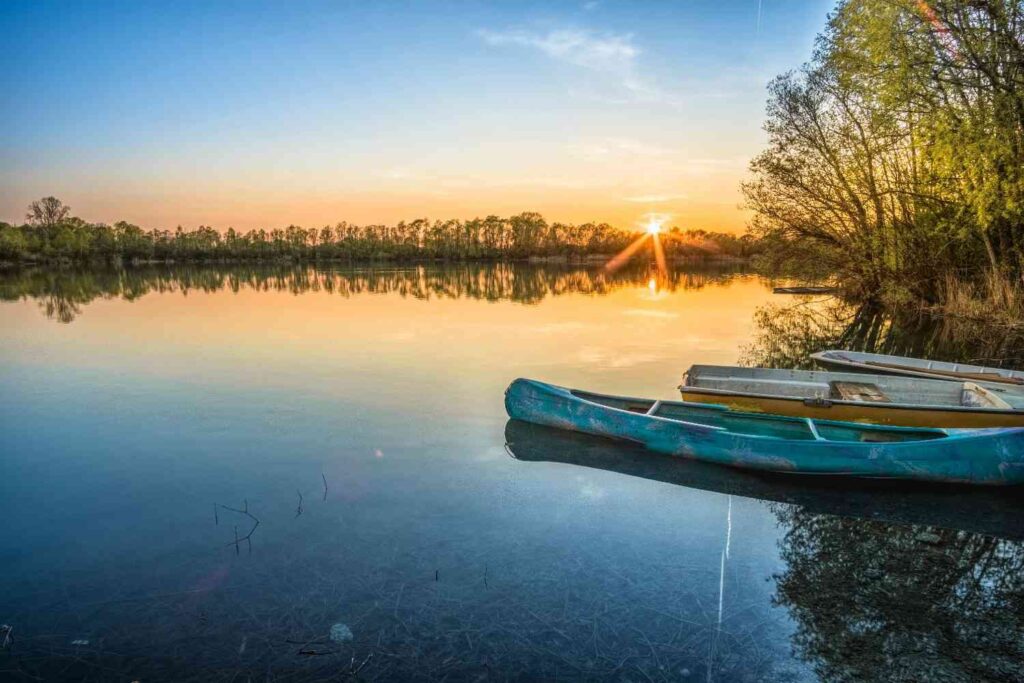 Kayaks parked near a calm lake at sunset