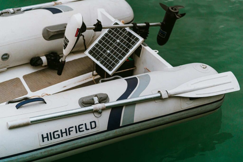 Inflatable boat with solar panel and trolling motor battery setup on water