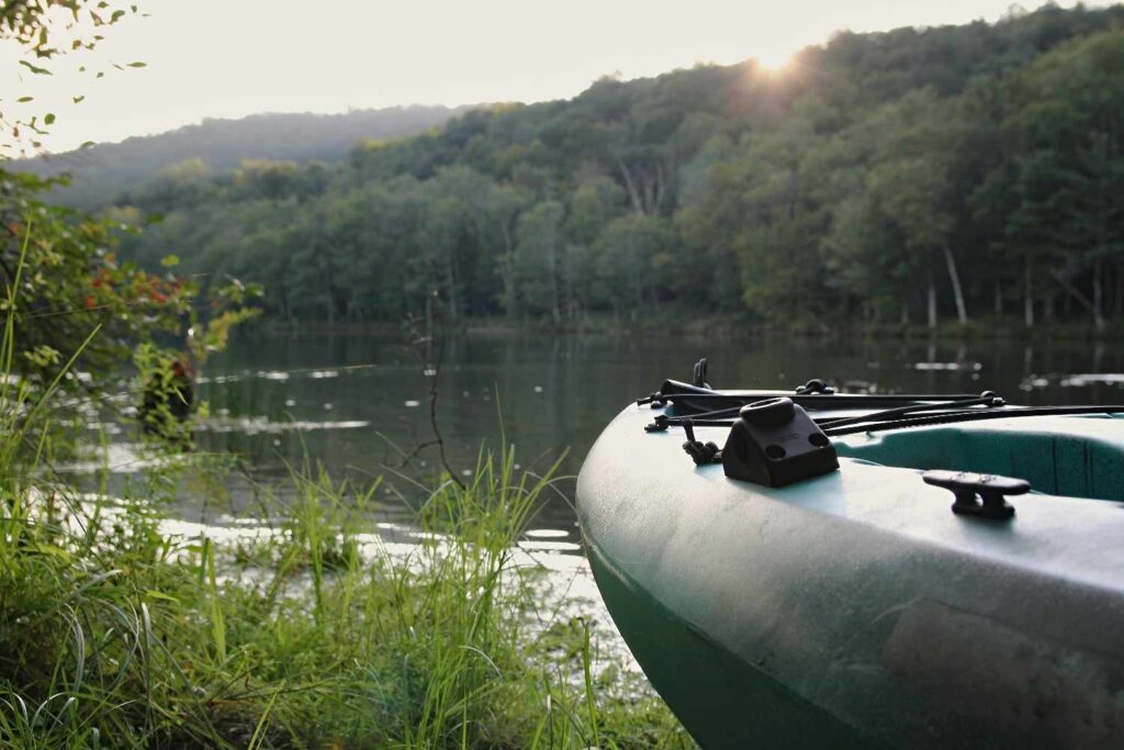 Close-up of fishing kayak bow with transducer mount near calm lake