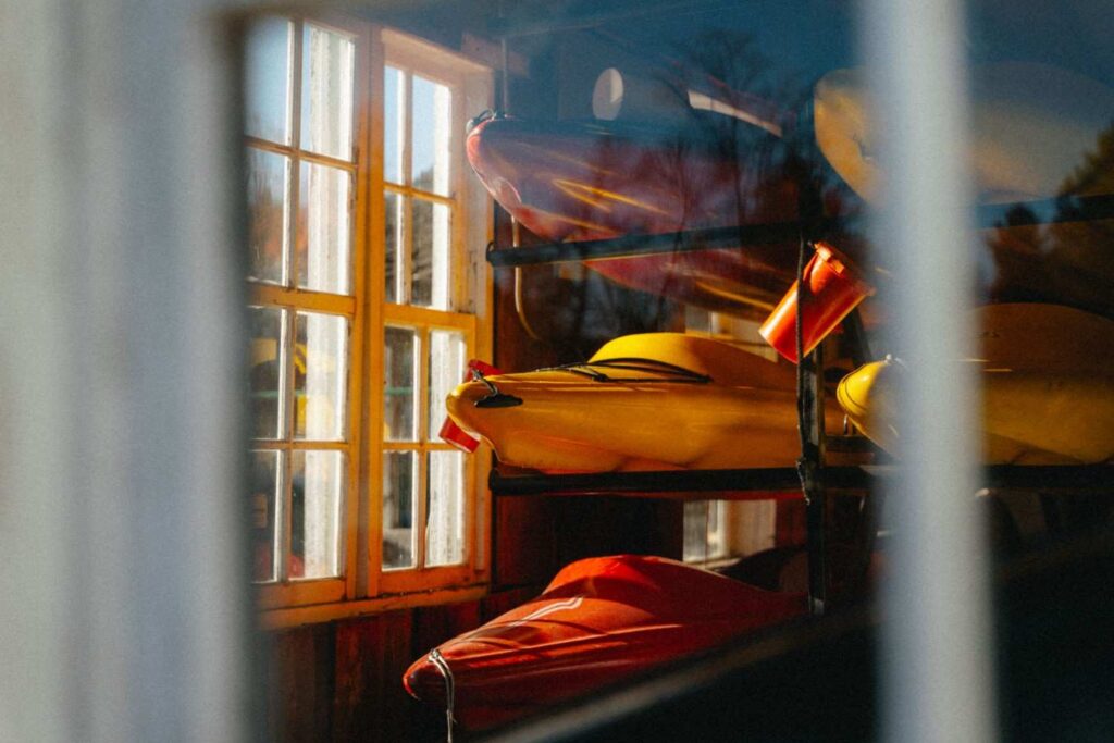 Kayaks stored on indoor wooden rack near a window
