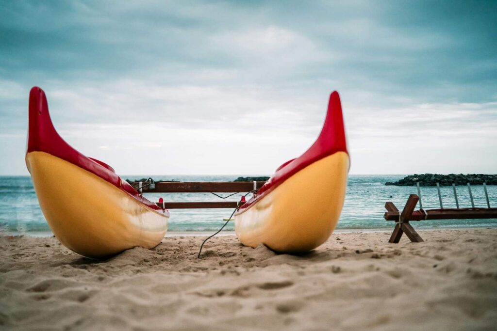 Two kayaks stored upside down on sandy beach near water