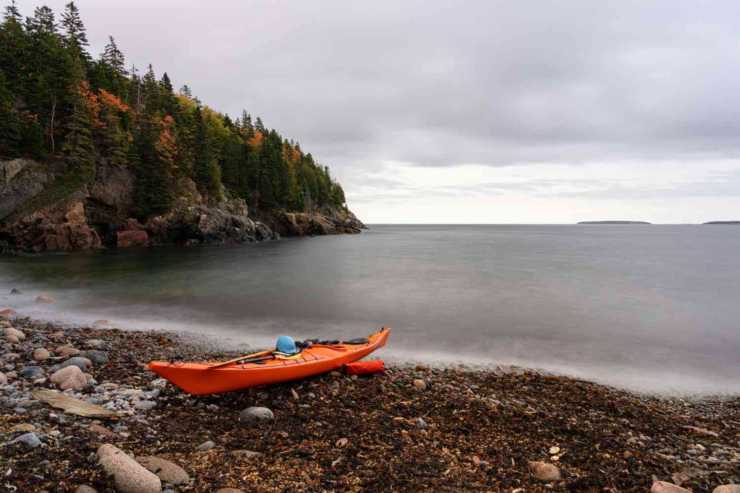 orange kayak on rocky shore ready to enter water