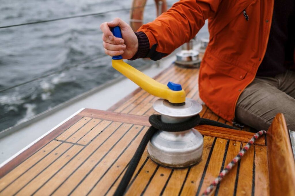 Hand gripping a wide, non-slip boat winch handle on deck, illustrating the importance of ergonomic grip design
