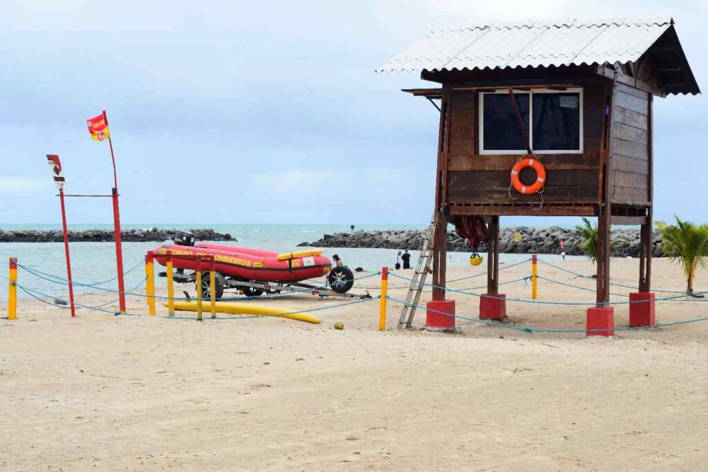 An inflatable boat secured with straps on a wheeled trailer at the beach