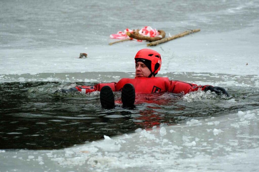 A person in a red immersion suit floats calmly in icy water without panicking