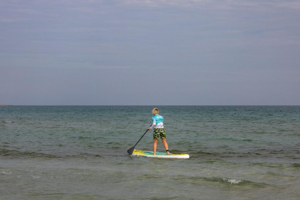 Woman paddleboarding with steady technique on calm open sea water