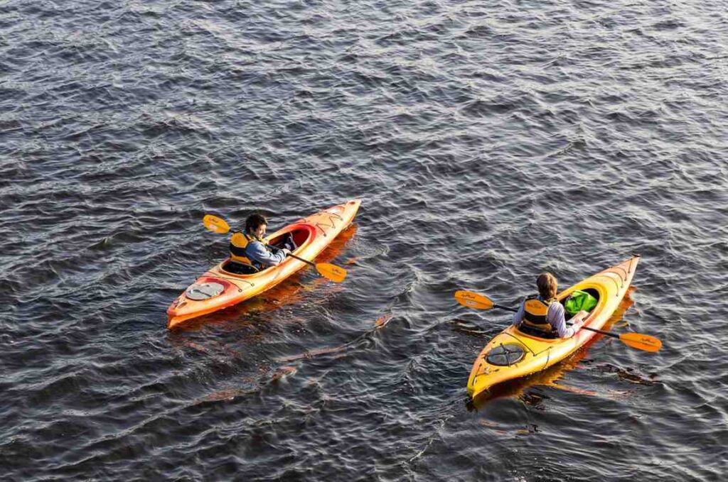 Aerial view of two paddlers in orange and yellow kayaks gliding across open rippling water