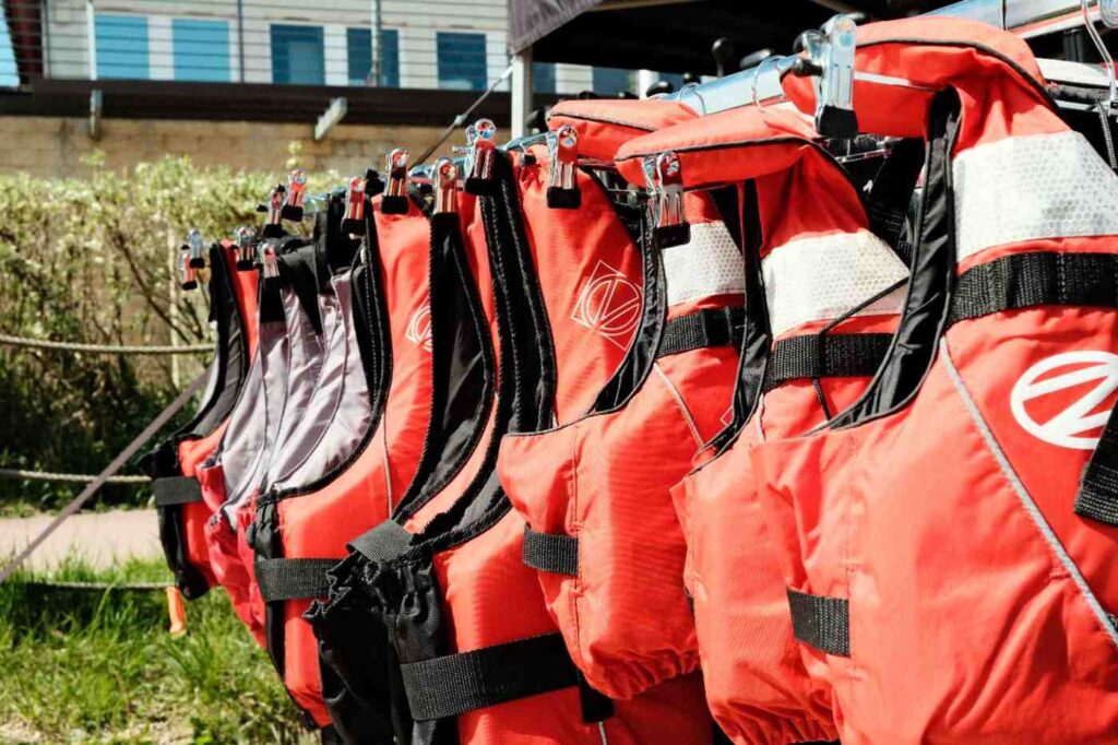 Multiple orange life jackets hanging in a row, essential safety gear for kayaking