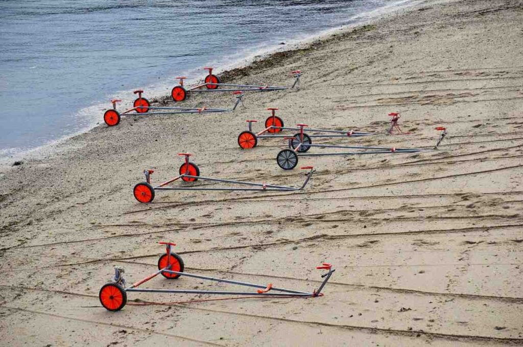 Several small wheeled launching trolleys lined up on a beach shoreline
