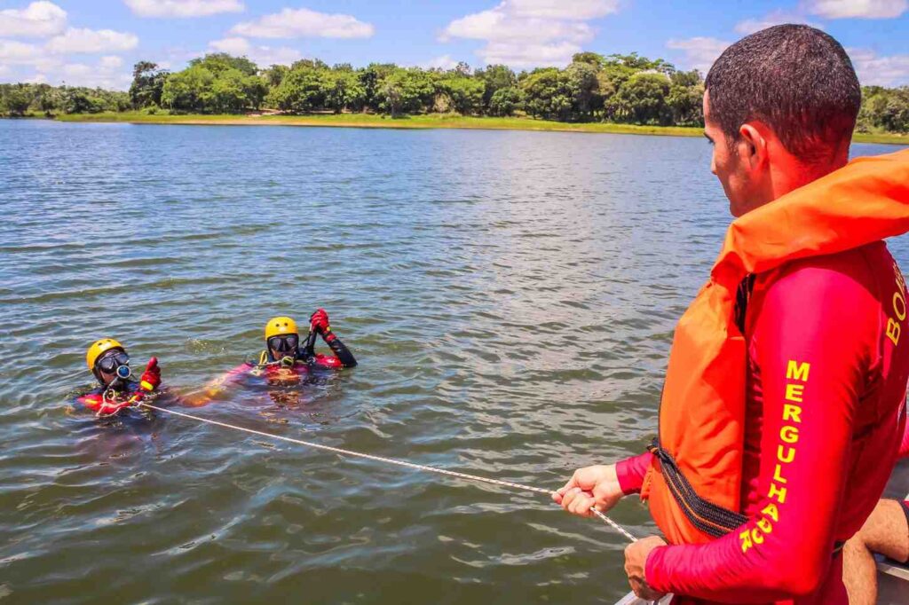 Two people in the water are guided back toward a boat using a rope for support