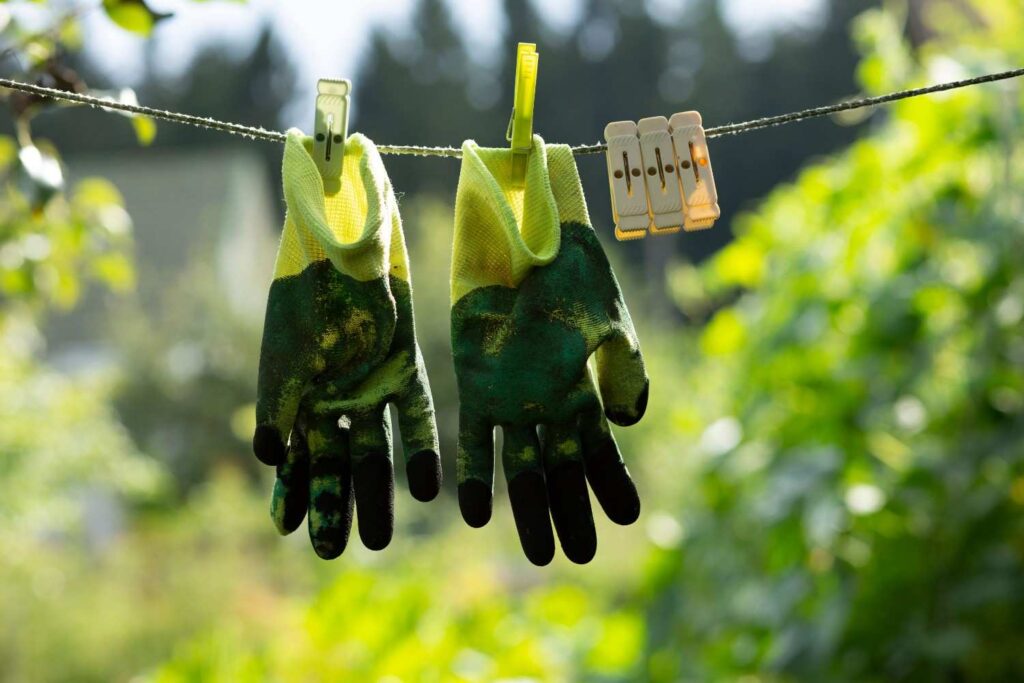 Textured gloves hanging to dry on a clothesline outdoors, illustrating proper post-use care