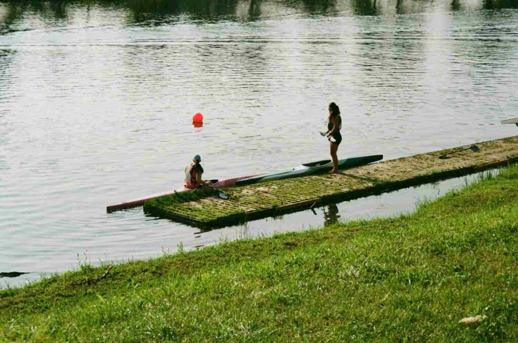Two women preparing to launch kayaks from a stable dock while wearing life jackets