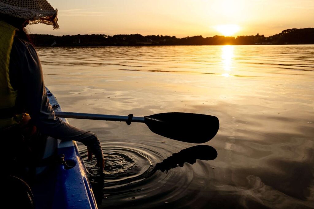 Kayaker paddling calmly on still water during sunset