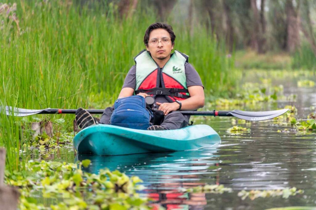 Man sitting in a wide, stable kayak wearing a life jacket on calm water